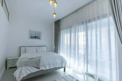 a white bedroom with a bed and a large window at Dubai Marina - 1BHK Cozy Vacation Homes near Metro in Dubai