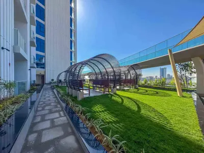 a walkway with benches and grass on a building at Frank Porter - Skyz By Danube in Dubai