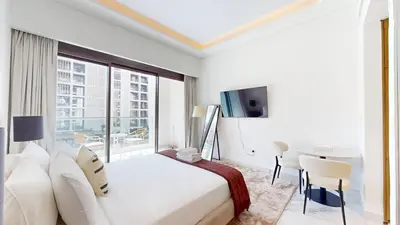 a white bedroom with a large bed and a desk at Luxurious Chic Comfort Studio in Dubai