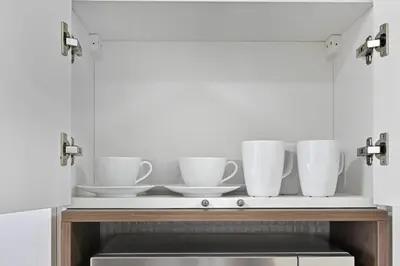 a shelf with white cups and saucers on it at Bloomfields Stunning STU, Elz By Danube, Dubai in Dubai
