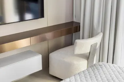 a bedroom with a white chair and a tv at Serene Creek Harbour Escape with Burj Khalifa View in Dubai