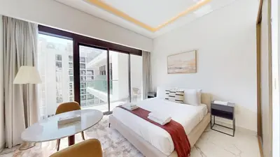 a white bedroom with a bed and a glass table at Modern Furnished Studio Azizi Riviera in Dubai