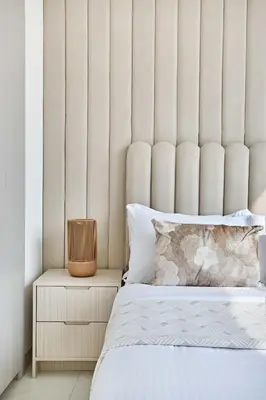a bedroom with a large white padded headboard at Frank Porter - The Crest Tower, Sobha Hartland in Dubai
