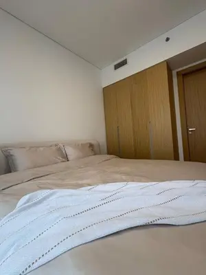 a white bed in a room with a wooden cabinet at Lux 2 Bedroom Cozy Family Getaway Home in Dubai