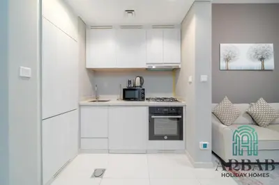 a kitchen with white cabinets and a couch in a room at Arbab Homes Luxury 1BR - Canal View - Damac Zada Tower in Dubai