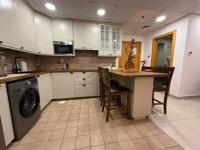 a kitchen with white cabinets and a table and a dishwasher at Modern 1-BR in Armada Tower 3, JLT, Sky Views in Dubai