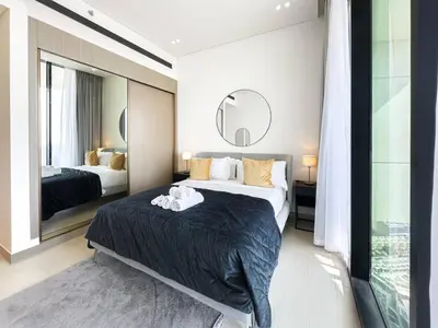 a bedroom with a large bed and a mirror at Modern and Cozy 1 Bedroom with Private Balcony Pool in Dubai