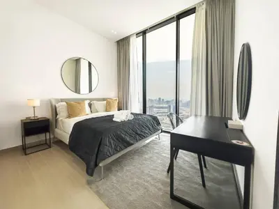 a bedroom with a bed and a desk and a mirror at Modern and Cozy 1 Bedroom with Private Balcony Pool in Dubai