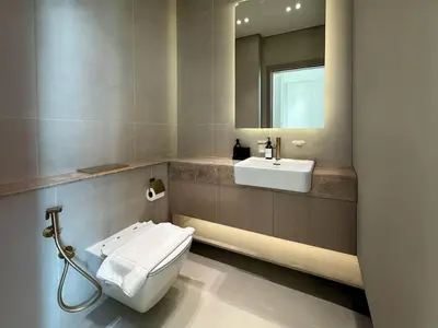 a bathroom with a toilet and a sink and a mirror at Modern and Cozy 1 Bedroom with Private Balcony Pool in Dubai