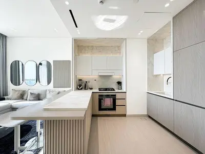 a kitchen with white cabinets and a couch in a room at Modern and Cozy 1 Bedroom with Private Balcony Pool in Dubai