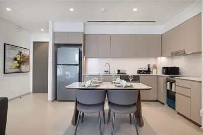 a kitchen with a table and two bar stools at Mahogany 24 - 2BR 6 PAX - On the Boulevard Sea View in Dubai