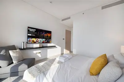 a white bedroom with a bed and a couch at Mahogany 24 - 2BR 6 PAX - On the Boulevard Sea View in Dubai