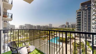 a balcony with a table and chairs and a pool at Vacationer l Upgraded Aesthetic 2 Bed l near Dubai Hills Mall in Dubai