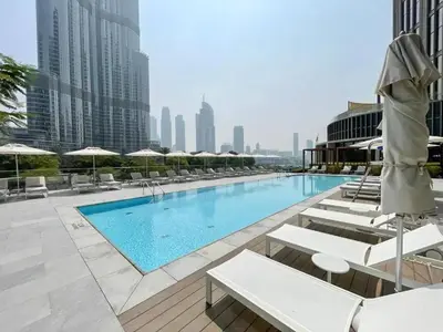 a swimming pool with chairs and umbrellas on a building at Vacationer l Elegant 2 Bed l near Burj Khalifa l Address Opera in Dubai
