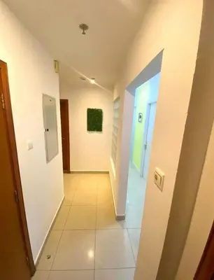 a hallway with white walls and a green painting on the wall at Quiet Comfort Room In Barsha Heights Tecom in Dubai