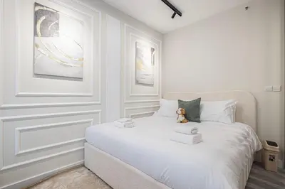 a white bedroom with a bed with a teddy bear on it at Chic JBR Apartment Beach Walk Dining Nightlife in Dubai