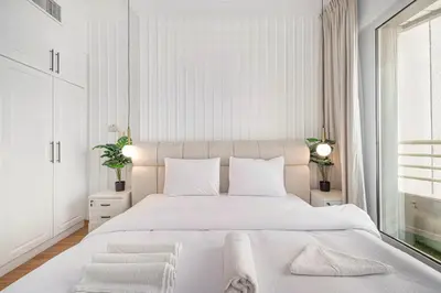 a white bedroom with a large bed and a window at Luxury 3BHK with floating bed in Marina in Dubai