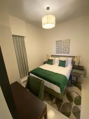 a bedroom with a bed with green sheets and a table at Ghalia in Dubai