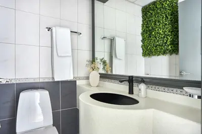 a bathroom with a sink and a toilet and a mirror at Frank Porter - Opal Tower in Dubai