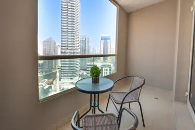 a table and chairs in a room with a window at Elegant Marina Living Manchester Tower in Dubai