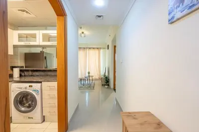 a hallway leading to a kitchen with a washing machine at Elegant Marina Living Manchester Tower in Dubai