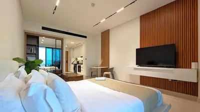 a bedroom with a white bed with a flat screen tv at Sleek and Cozy Studio, Private Jacuzzi, Canal View in Dubai