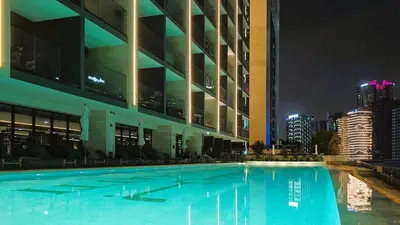 a large swimming pool in front of a building at night at Sleek and Cozy Studio, Private Jacuzzi, Canal View in Dubai