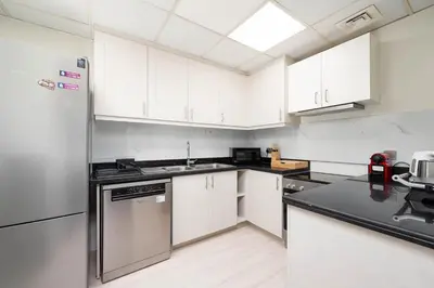 a kitchen with white cabinets and a black counter top at Bright Apartment with Large Balcony and Water View in JBR in Dubai