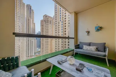 a balcony with a couch and a table and a window at Bright Apartment with Large Balcony and Water View in JBR in Dubai