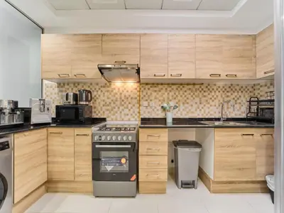 a kitchen with wooden cabinets and a stove at Cozy 2BR Canal Residence Sports City in Dubai