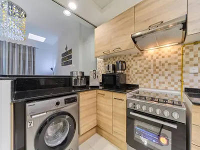 a kitchen with a washing machine and a washer at Cozy 2BR Canal Residence Sports City in Dubai