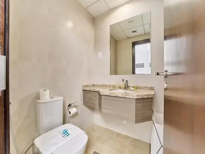 a bathroom with a toilet and a sink and a mirror at Cozy 2BR Canal Residence Sports City in Dubai