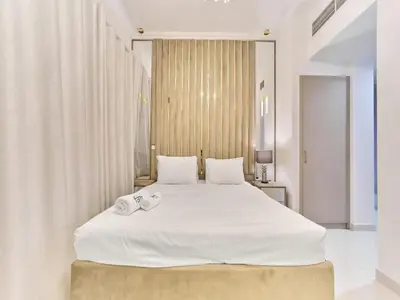 a bedroom with a large white bed with towels on it at Cozy 2BR Canal Residence Sports City in Dubai