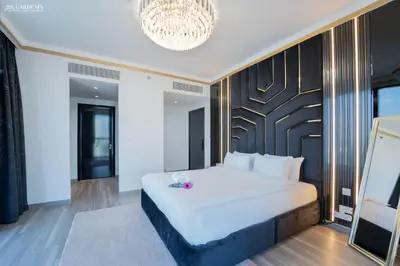 a bedroom with a large white bed and a chandelier at Blvd Point-Full Burj Khalifa View-Downtown in Dubai