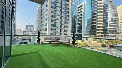 a balcony with a couch and a green lawn at 1BDR with Huge Balcony Stylish Living in Dubai