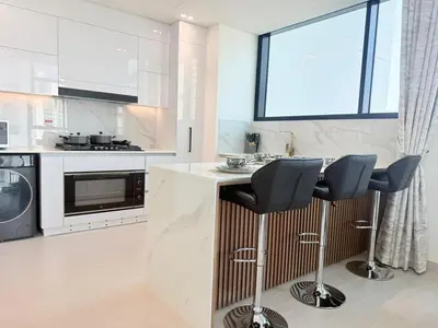 a kitchen with a counter and two stools at Binghatti Gardenia 2BHK in JVC in Dubai