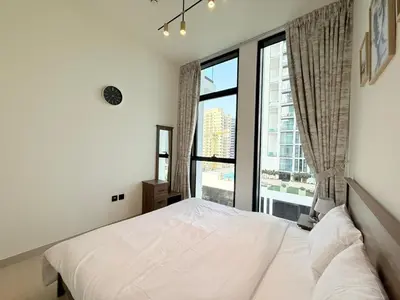 a bedroom with a white bed and a large window at Binghatti Gardenia 2BHK in JVC in Dubai