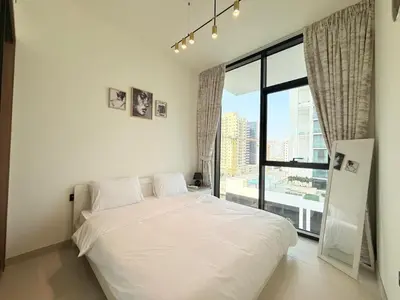 a bedroom with a white bed and a large window at Binghatti Gardenia 2BHK in JVC in Dubai