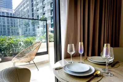a table with two plates and wine glasses and a window at Sleeps 3 Studio JVC I Fully Furnished I Central in Dubai