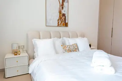 a white bed with white sheets and pillows at Sleeps 3 Studio JVC I Fully Furnished I Central in Dubai