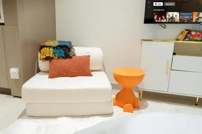 a living room with a chair and a table at Sleeps 3 Studio JVC I Fully Furnished I Central in Dubai