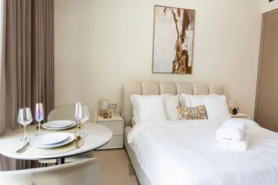 a bedroom with two beds and a table with chairs at Sleeps 3 Studio JVC I Fully Furnished I Central in Dubai