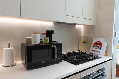 a kitchen with a microwave and a stove at Sleeps 3 Studio JVC I Fully Furnished I Central in Dubai