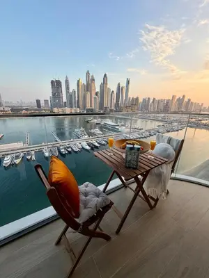 a table and chairs on a balcony with a view of a city at Ultra Luxury Emaar Beachfront Flat With Private Beach in Dubai