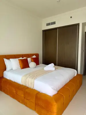 a large bed with white sheets and orange pillows at Ultra Luxury Emaar Beachfront Flat With Private Beach in Dubai