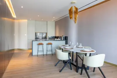 a dining room with a table and chairs and a kitchen at The Opus Residences 1 Bedroom in Dubai