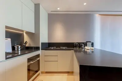 a kitchen with white cabinets and black counter tops at The Opus Residences 1 Bedroom in Dubai