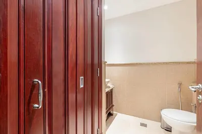 a bathroom with a toilet and a wooden door at Massive 2,000 sqft 1BR with Private Terrace & BBQ in Dubai