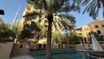 a palm tree in front of a building with a swimming pool at Massive 2,000 sqft 1BR with Private Terrace & BBQ in Dubai
