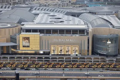 a large building with a billboard on the side of it at Modern 2BR, Burj & Fountains View, Dubai Mall 2 Minutes Walk in Dubai